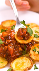 a hand with a fork and a plate of country styled potatoes