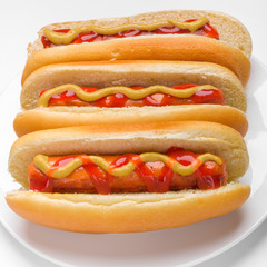 three classic hotdogs with mustard and ketchup on a plate