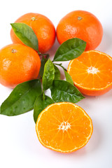 a group of four tangerines with leaves, one cut in half