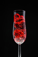 red jelly hearts in champagne glass on black background