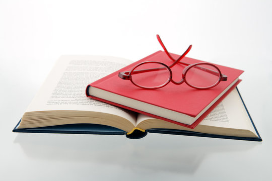 red blue books reading glasses  reflecting white surface