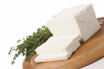 goat's milk cheese in block, sliced with savory on white