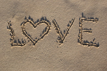 Love sign written on sand with heart shape