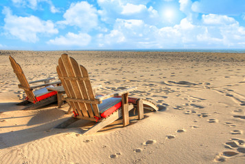Fototapeta na wymiar Two beach chairs sitting in the sand