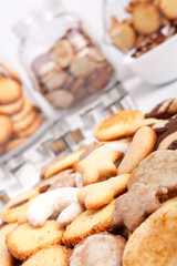 a big pile of various cookies with three cookie jars at the back
