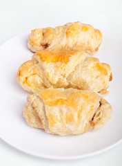 three sausage rolls on a white plate on a white background