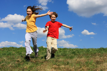 Kids jumping, running against blue sky