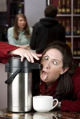 Gordijnen Woman drinking coffee directly from a dispenser © Scott Griessel