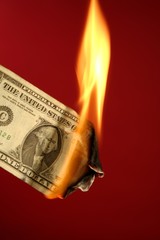 Dollar note burning in fire over red