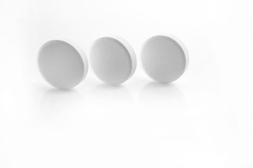 Three isolated white round pills