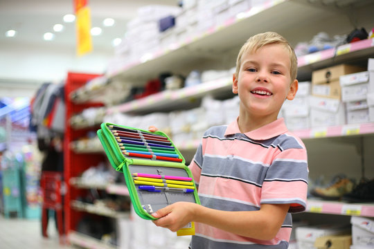 Boy with colour pencils in shop