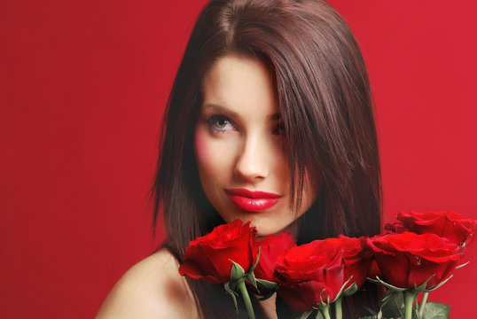 Beautiful woman with a magic rose over red background