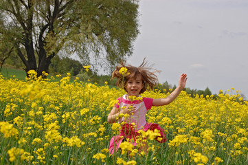 Fototapeta premium Happy girl jumping on canola field