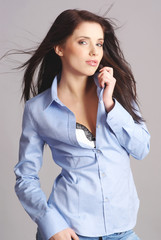 Portrait of sexy woman wearing blue shirt on grey background.