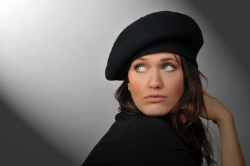 Woman with beret looking toward shaft of light.