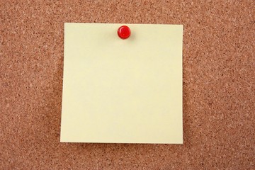 cork board with blank note attached with thumb pin
