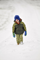 Fototapeta na wymiar Little boy walking in snow.