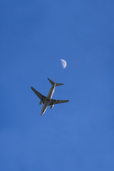Fototapeta premium Ein Flugzeug im Flug von direkt unterhalb, mit Mond