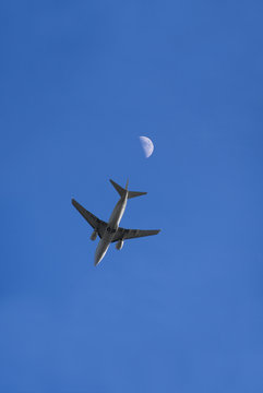 Ein Flugzeug im Flug von direkt unterhalb, mit Mond