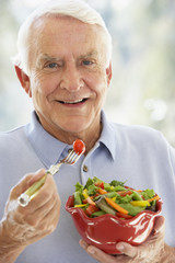 Senior Man Smiling At Camera And Eating Salad