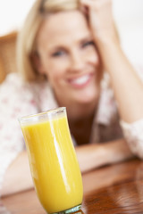 Mid Adult Woman Looking At A Glass Of Fresh Orange Juice