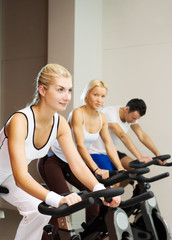 Fototapeta na wymiar Group of people doing exercise on a bike in a gym