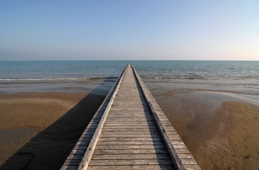 Fototapeta na wymiar Wooden pier perspective on seashore