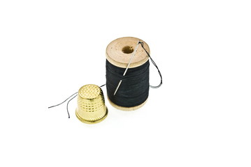 a spool of thread with a needle in it and thimble