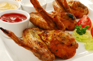Grilled chicken wings with baked potatoes and vegetable salad