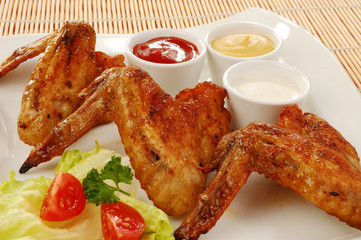 Grilled chicken wings with baked potatoes and vegetable salad