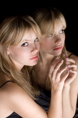 Portrait of the young beautiful blonde near a mirror