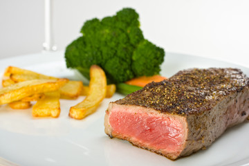 gegrilltes Steak auf einem Teller mit Pommes frites und Gemüse
