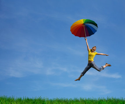 Flying girl with colorful umbrella on the blue blue sky