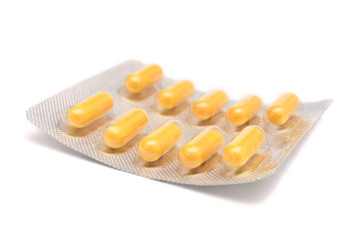 Yellow pills in a blister isolated on white.