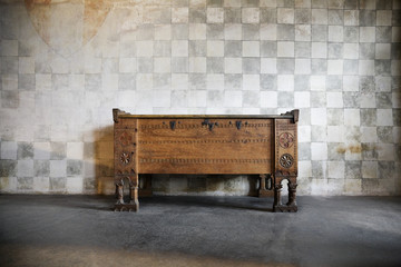 an antique wooden chest of drawers in castle at a stone wall