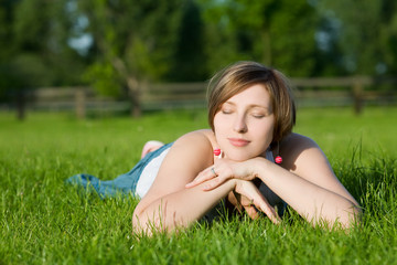 Naklejka na ściany i meble Beautiful woman laying on grass