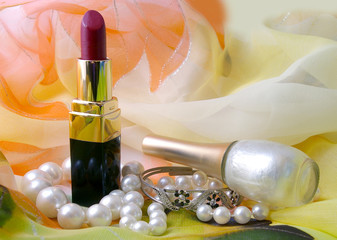 lipstick and necklace on background silk fabrics