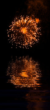 Explosive fireworks shooting into the black sky and reflections