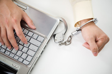 Handcuffed businessman on laptop