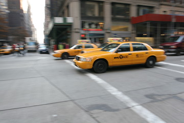 Three fast driving yellow cabs (Taxi car) in Manhattan Soho in New York City, USA