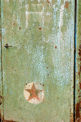 Old green gate with cracked paint and Soviet star sign