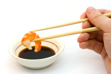 Shrimp in chopsticks and soy sauce.