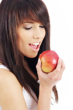 Beautiful young woman eating red apple. Isolated over white
