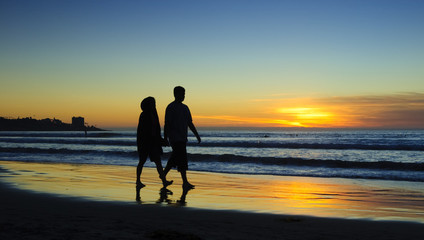 Fototapeta premium Couple walking on the beach at sunset