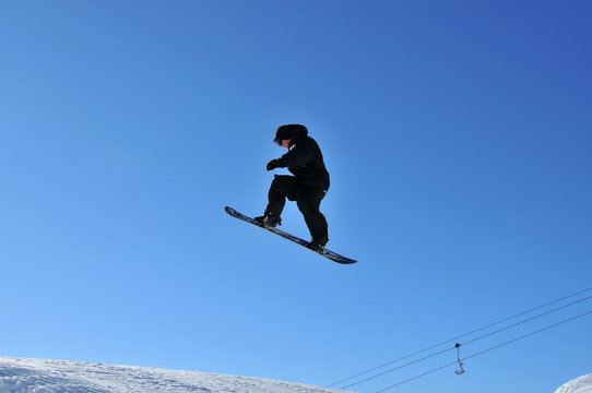 snoboarder in black on a high jump