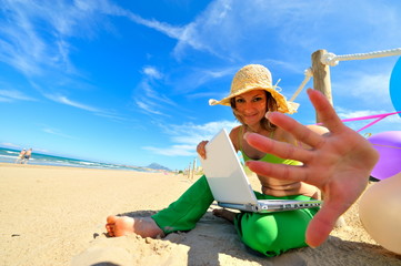 young woman with colorful balloons using laptop on the beach