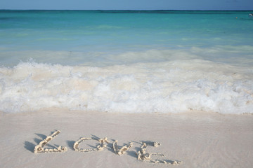 Word Love on Beach Sand on White Sand Beach and Green Ocean