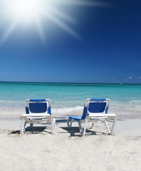 Two Lounge Chairs on White Sand Beach and Ocean Background