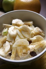 Bircher Muesli with fresh fruits, banana and raisins in a morning light atmosphere.