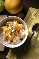 Still-life of a Bircher Muesli with fresh fruits and hazelnuts in a morning light atmosphere taken on a kitchen table.